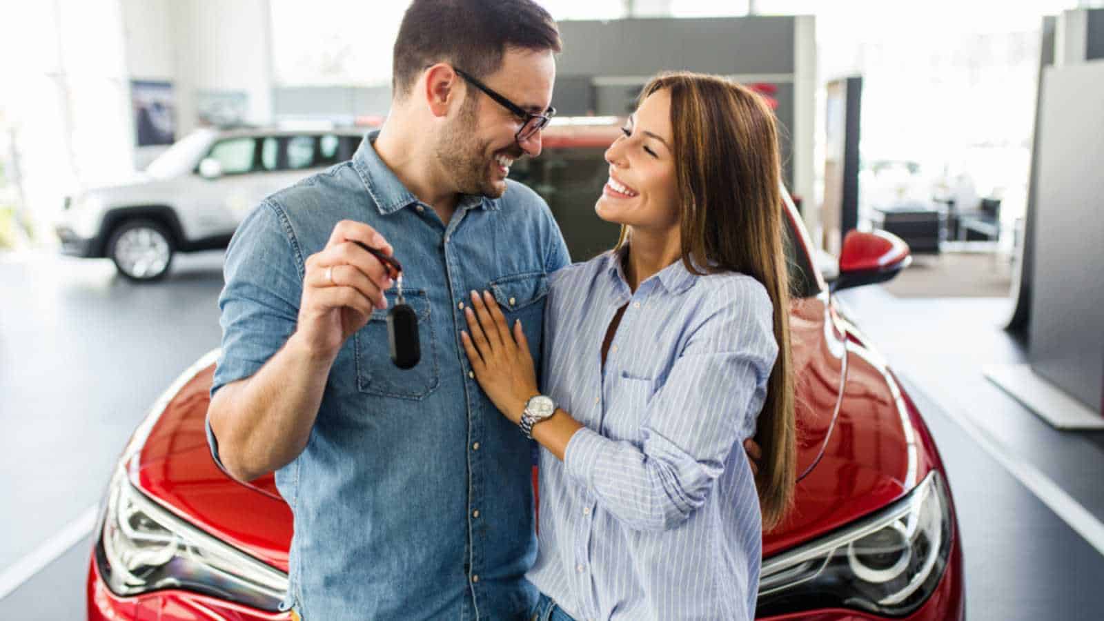 Beautiful young smiling couple holding a key of their new car.